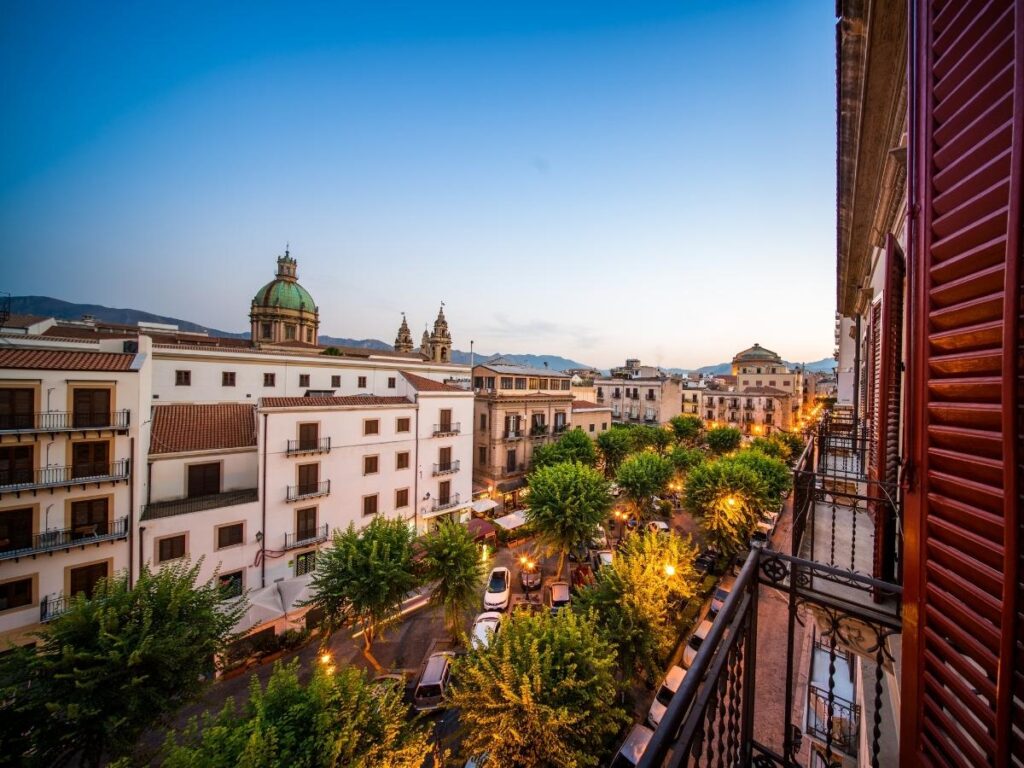 View from a balcony overlooking Palermo’s old town rooftops and domes at sunset