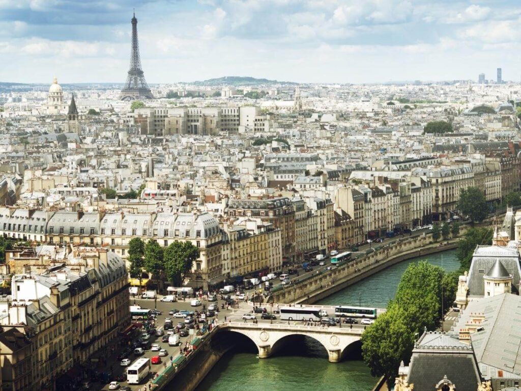 Panoramic view of Paris rooftops glowing at sunset, with the Eiffel Tower in the distance