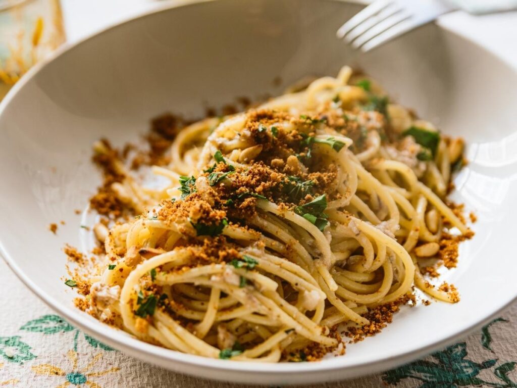 Plate of traditional pasta con le sarde with fennel, pine nuts, and raisins at a local trattoria in Palermo