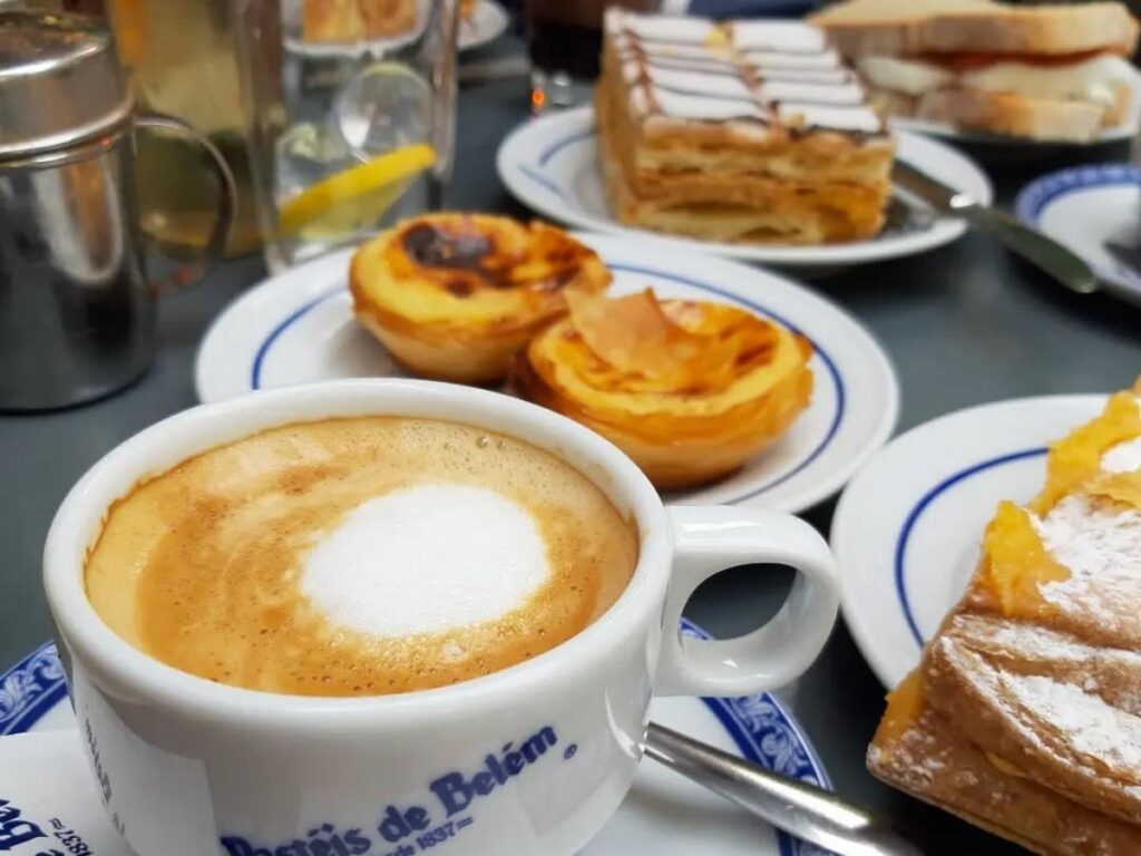 Fresh pastéis de nata dusted with cinnamon on a plate, steam rising from the warm custard