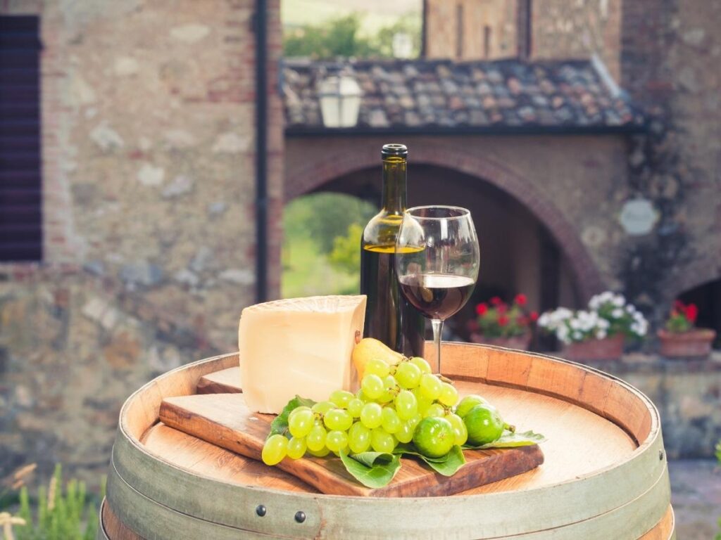Glass of Pecorino white wine with bruschetta topped with tomatoes and herbs, set outdoors on a summer afternoon.