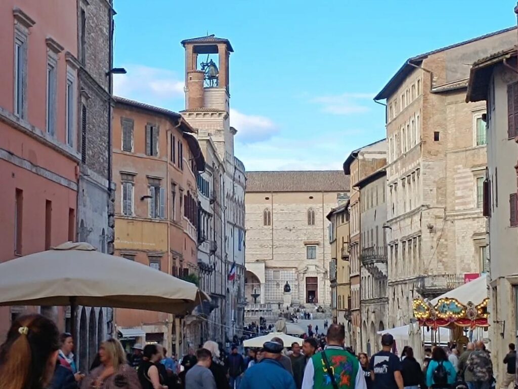 People sitting at sidewalk cafes along Corso Vannucci in Perugia, university buildings in the background