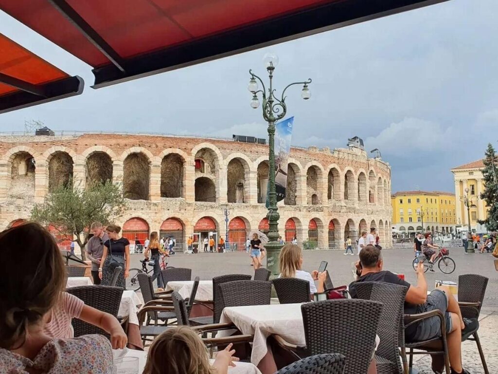 Early morning in Piazza Bra, Verona, with sunlight on the Arena and locals walking to cafés.”