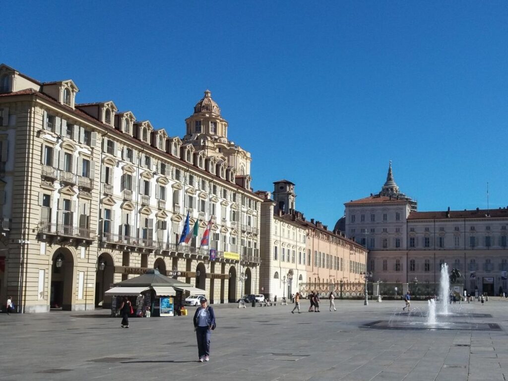 Locals walking through Piazza Castello in the soft morning light.