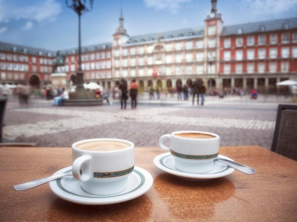 Locals having morning coffee at Plaza Mayor in Madrid under soft morning light