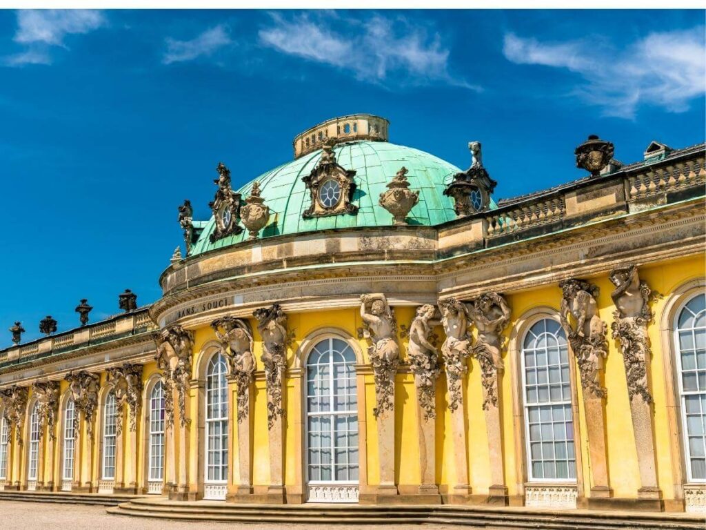 People walking along terraces of Sanssouci Palace in Potsdam surrounded by lush gardens