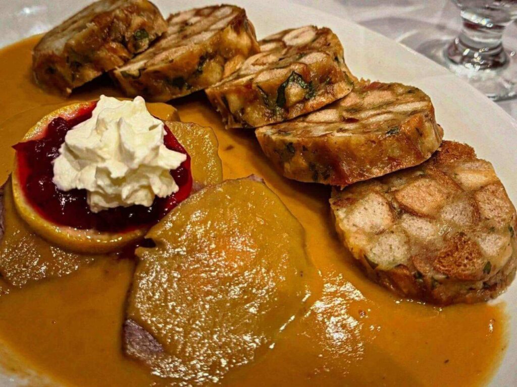 Plate of svíčková (marinated beef in cream sauce) served with bread dumplings at a traditional Czech restaurant.