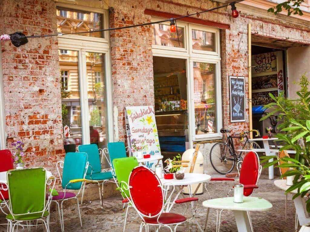 “Leafy street in Prenzlauer Berg with outdoor cafés, bicycles, and locals enjoying brunch.”