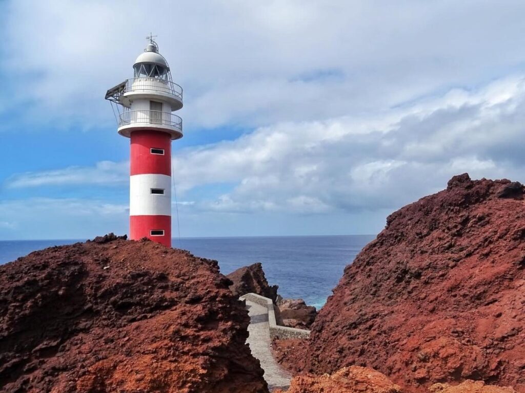 People swimming near the red lighthouse and wooden pier at Punta Faro, Lignano Sabbiadoro