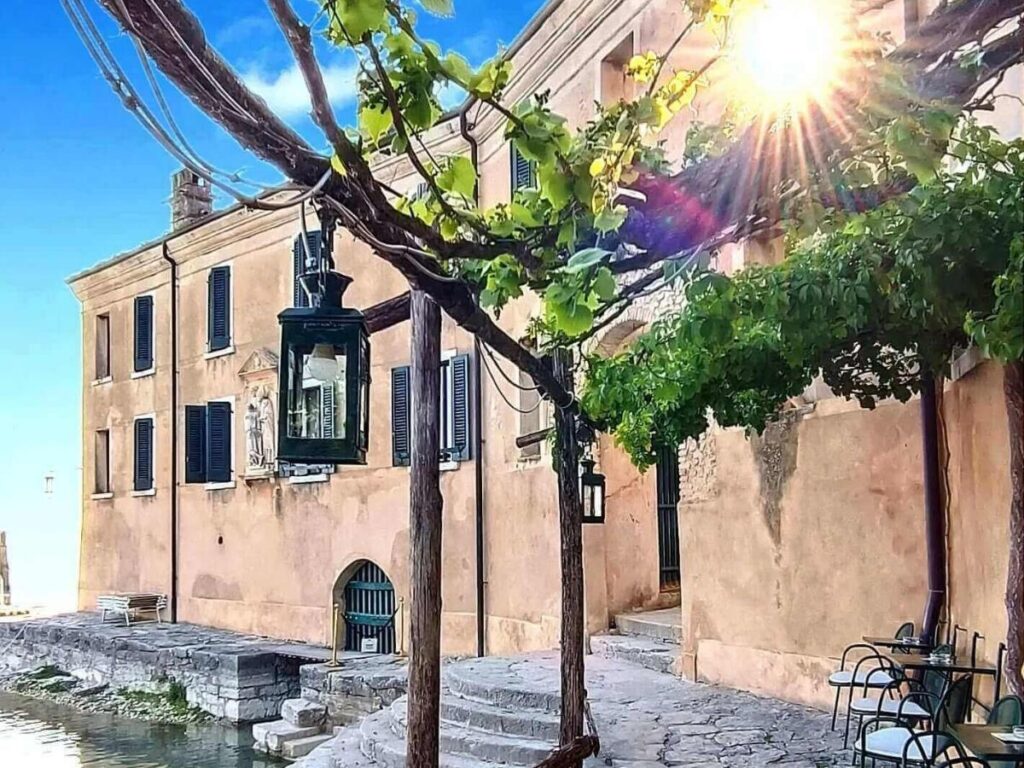 Punta San Vigilio bay with villa and cypress trees, view across Lake Garda