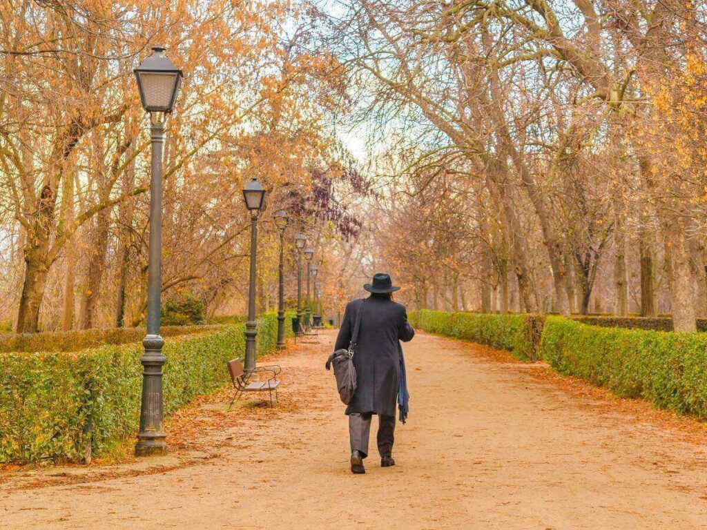 Couple walking through El Retiro Park in Madrid at sunset under warm golden skies