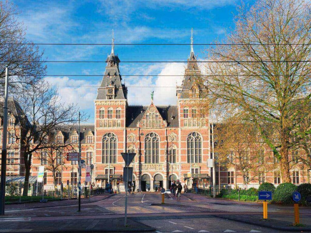 Entrance of the Rijksmuseum with people walking across Museumplein