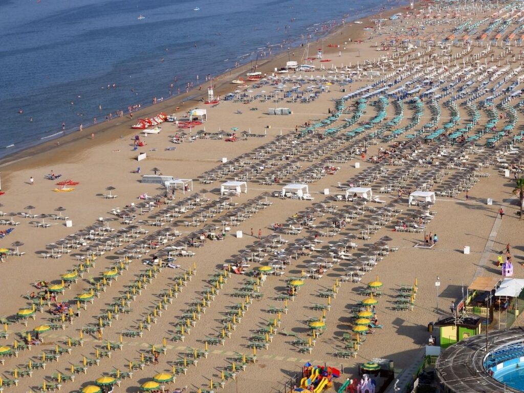 Paddleboarders off Rimini coast near calm Adriatic waters at sunrise.