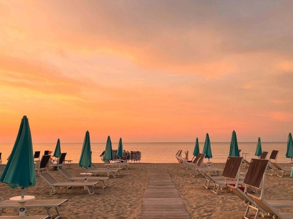 Quiet Rimini beach at sunset in September with soft golden light.