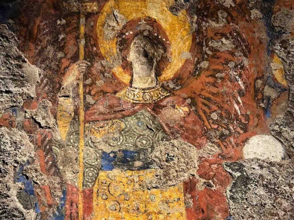 Inside a rock-cut rupestrian church in Matera with faded medieval frescoes on the walls.