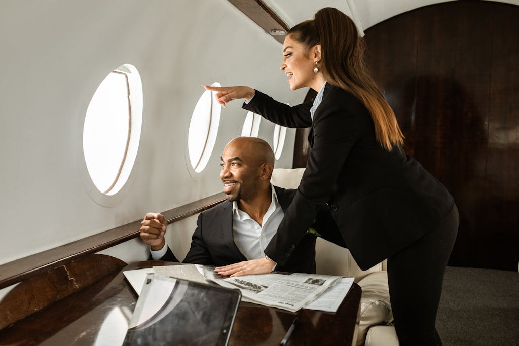 Smiling couple in a private jet, enjoying the view and reading newspapers together.