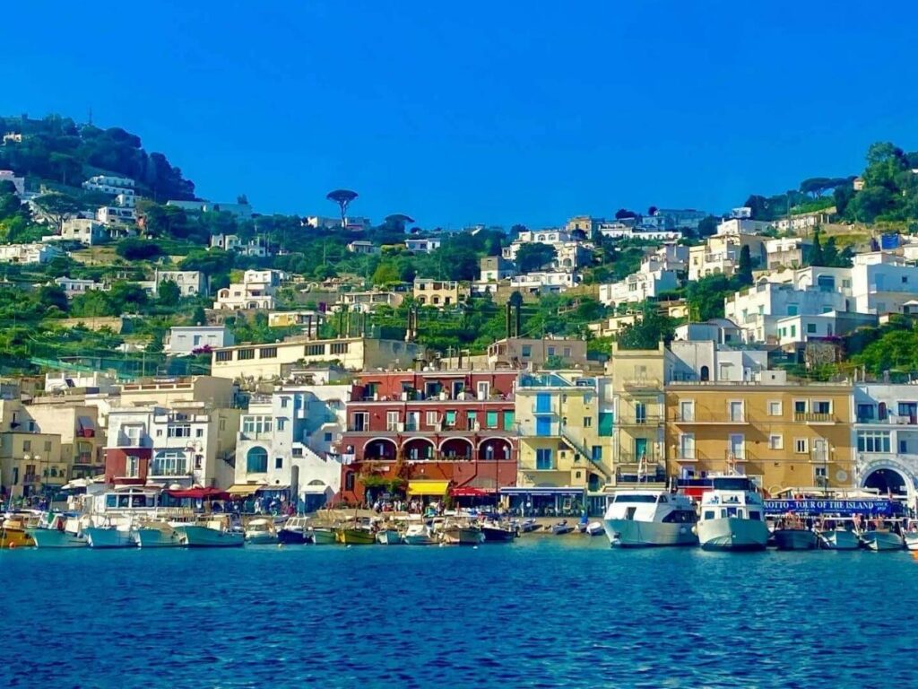 View from ferry leaving Marina Piccola in Sorrento with cliffs rising behind and Capri in the distance.