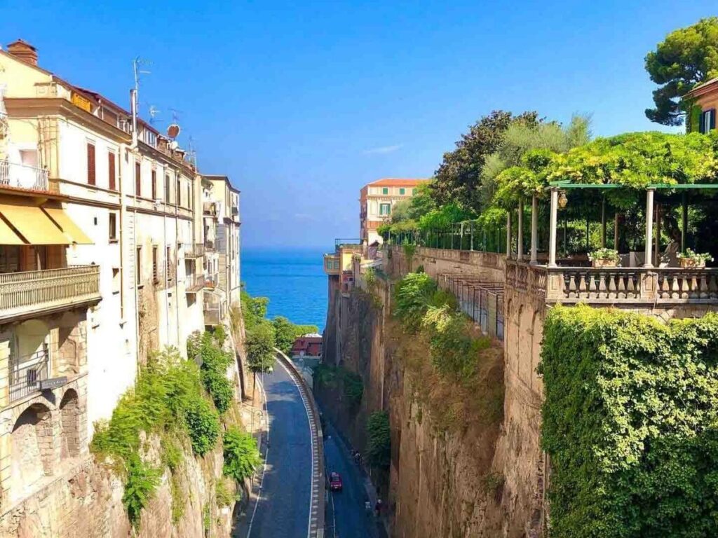 Morning sunlight over Piazza Tasso with locals walking past cafés and scooters parked along the square.