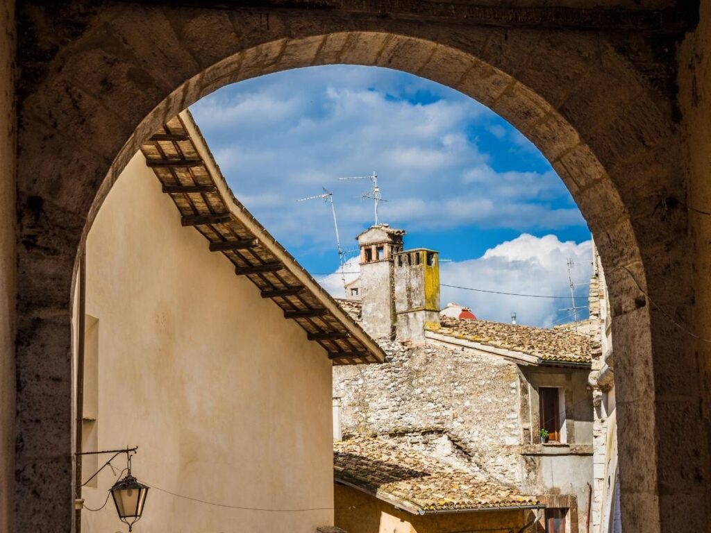Narrow stone street and Roman arch in Spoleto with a few pedestrians