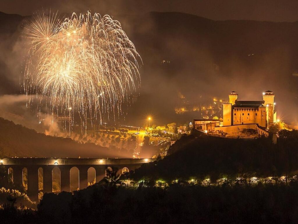 Outdoor evening performance during Festival dei Due Mondi in Spoleto with strings of lights and a seated crowd