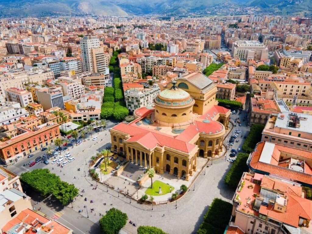 Evening lights of Teatro Massimo opera house in Palermo with people sitting on the steps