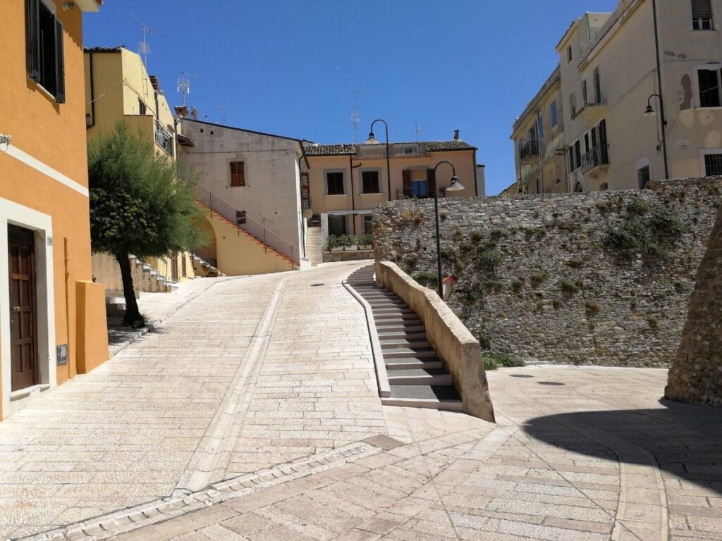 View of Termoli’s old borgo perched above the Adriatic Sea with pastel houses and fishing boats in the harbor