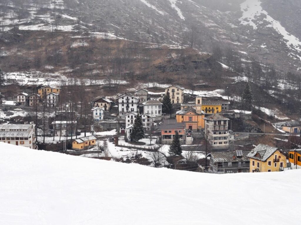 Castello di Aymavilles from below showing its four corner towers and stone exterior against a blue sky.