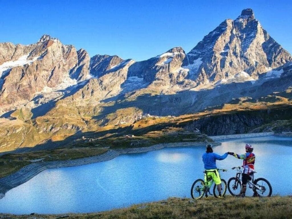Mountain biker dropping down a forested trail in Pila with chairlifts in the background