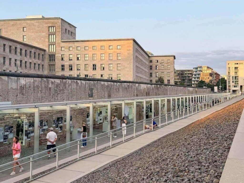 “Visitors walking through outdoor exhibits at Topography of Terror memorial site, Berlin