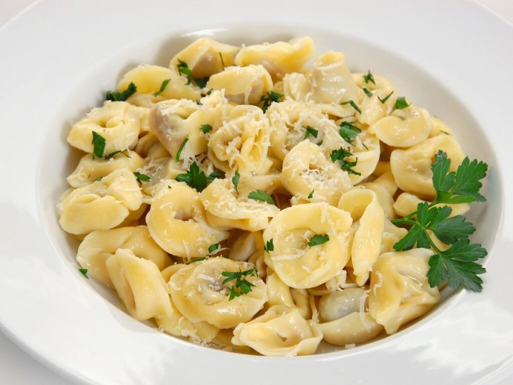 “Bowl of tortellini in brodo served in a rustic trattoria in Bologna.