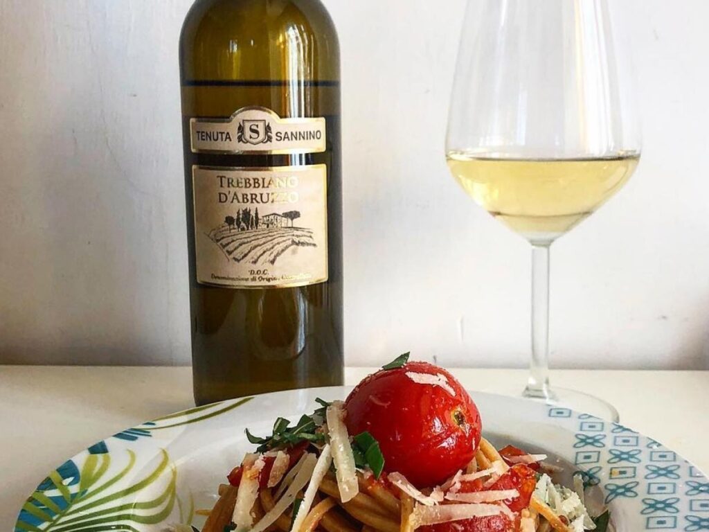 Chilled glass of pale Trebbiano d’Abruzzo on a trattoria table with fresh cheese and bread.