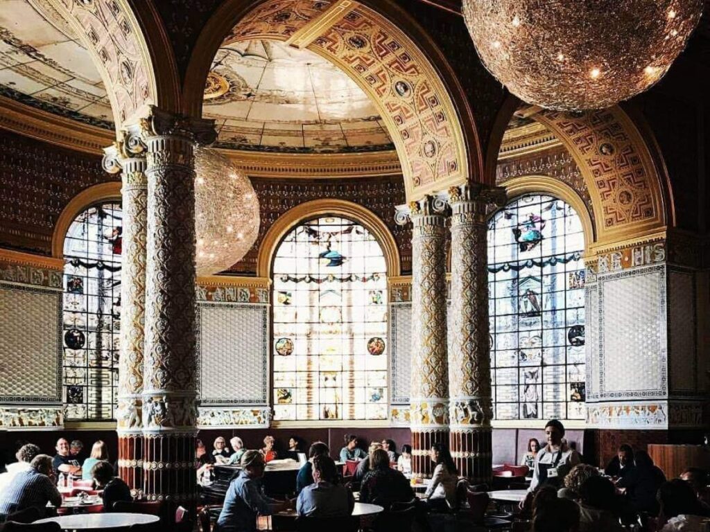 Visitors relaxing by the fountain in the Victoria and Albert Museum courtyard café, London.