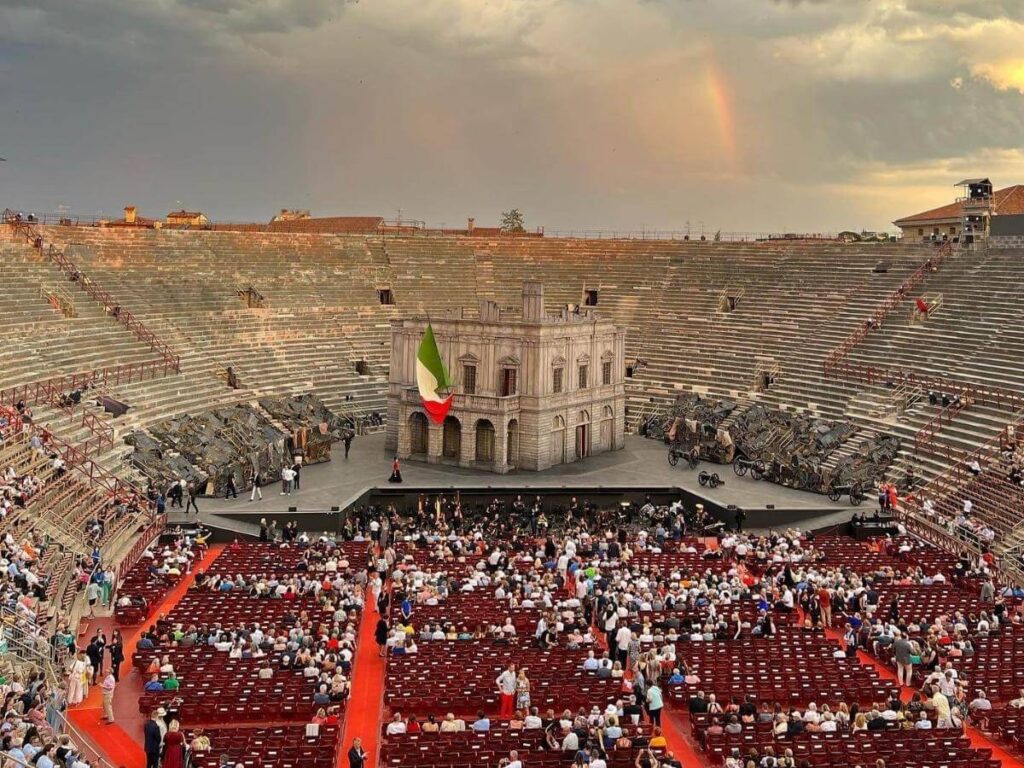 “Candlelit audience watching an opera performance at the Verona Arena under the night sky.”