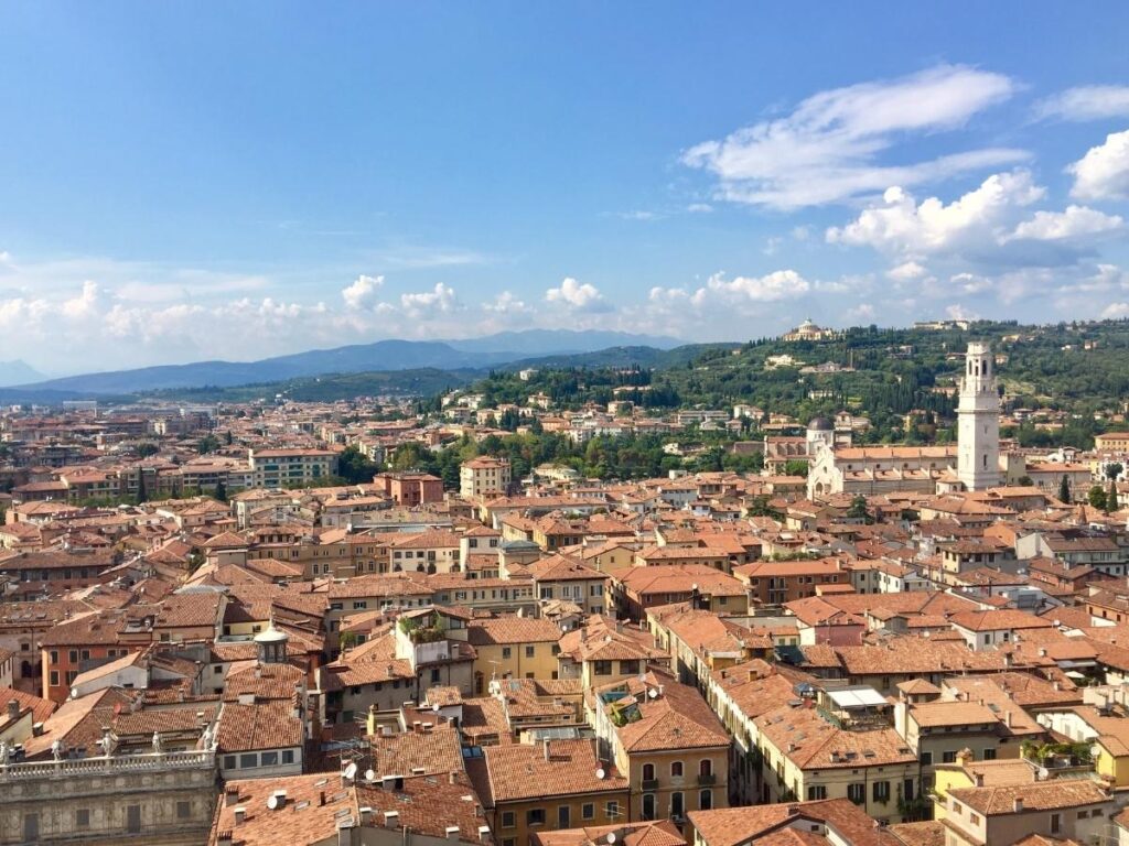“Narrow cobblestoned street with colorful buildings and cafés in Verona’s Centro Storico.”