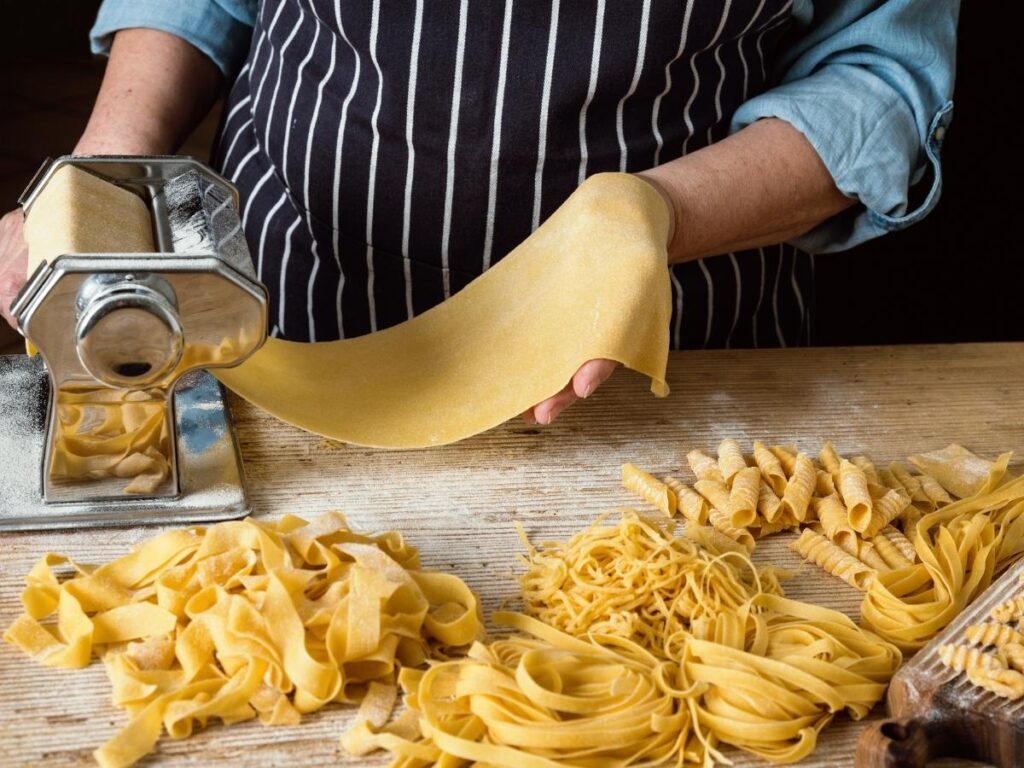 Hands making fresh pasta during a traditional cooking class in Verona, Italy.