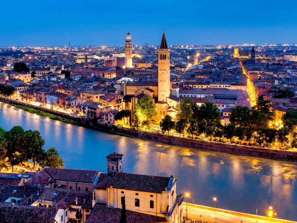 Panoramic view of Verona, Italy, with the Adige River curving around the historic old town at sunset.”