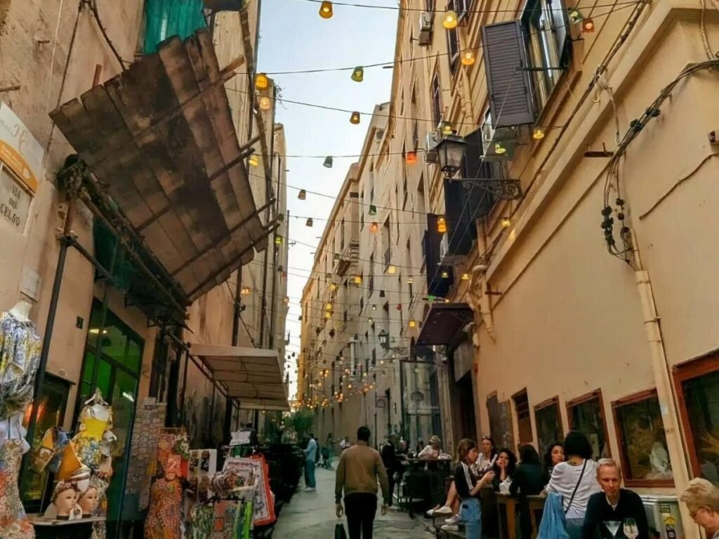 Pedestrian Via Maqueda street lined with old buildings, shops, and balconies in Palermo