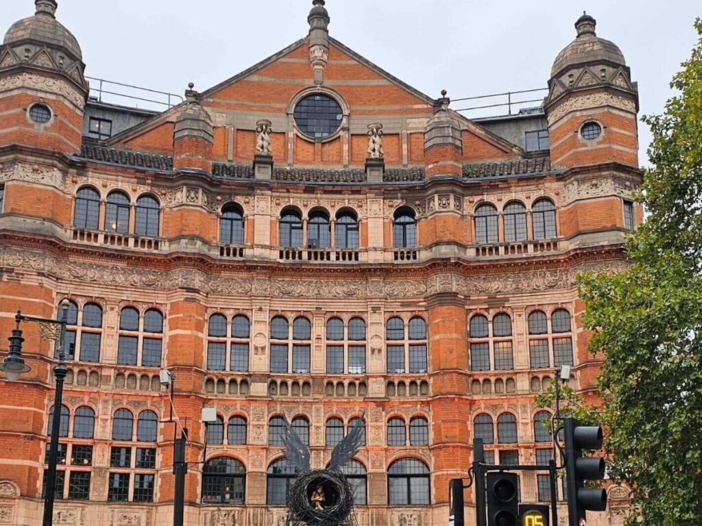 Crowds gathering outside West End theatres in London at night with illuminated marquees