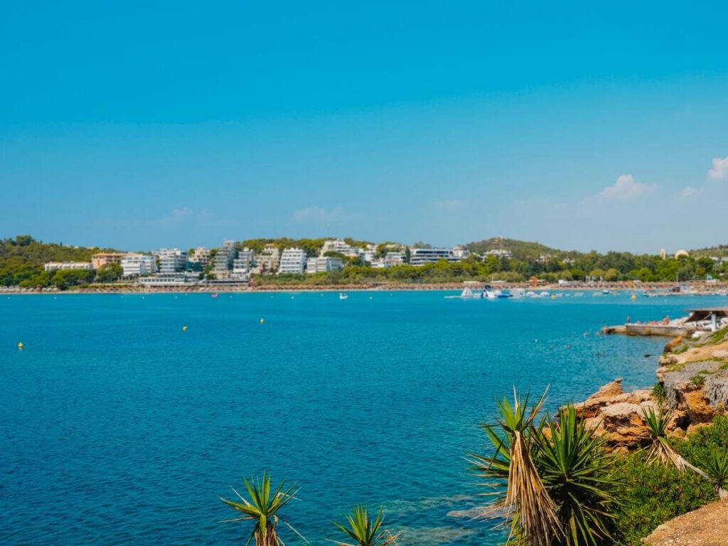 Calm morning at Akti Vouliagmenis with clear blue water and a few early swimmers