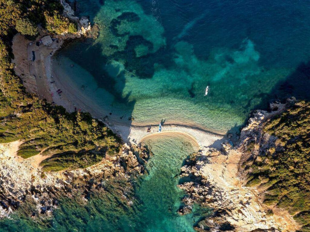 Early summer on the Albanian Riviera with calm turquoise water and nearly empty beach in soft morning light