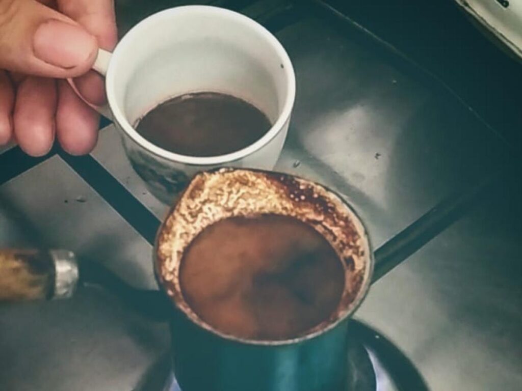 Traveler enjoying morning coffee by the water on the Albanian Riviera with boats in the distance