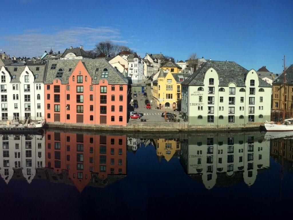 Boats and historic buildings reflected in the calm water of Brosundet canal, Ålesund