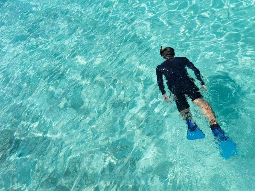 Person floating in crystal-clear turquoise water off Antipaxos, seabed visible below