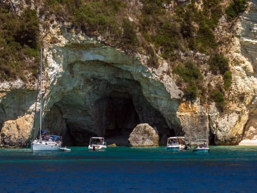 Rocky cave entrance opening to glowing blue water on the Antipaxos coastline