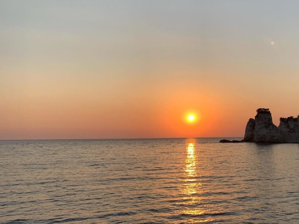 Sunset over the rugged coastline of Antipaxos with soft orange light on the water