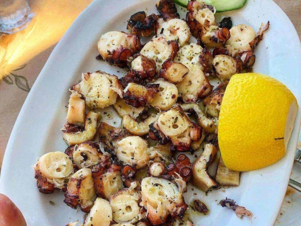 “Greek salad, grilled fish, and lemon served at a beach taverna on Antipaxos