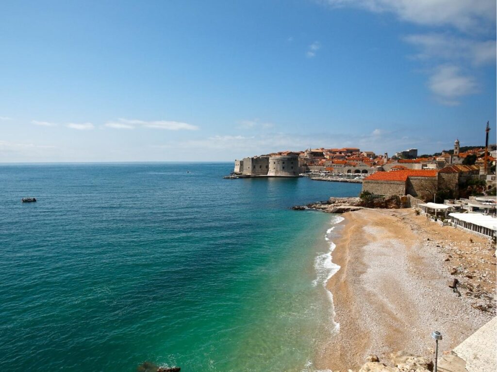 Banje Beach with swimmers and a clear view of Dubrovnik Old Town walls
