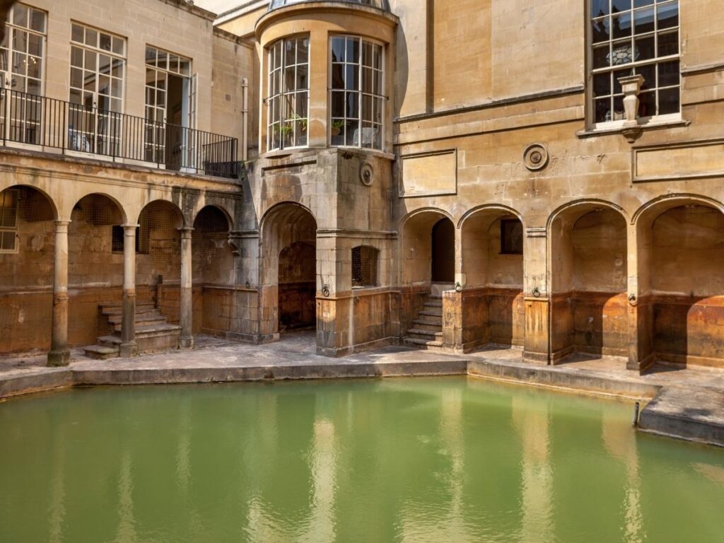 The Great Bath at the Roman Baths with rising steam and surrounding ancient stone columns