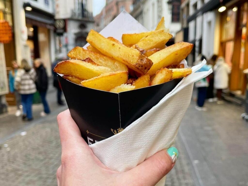 Thick Belgian fries served in a paper cone with dipping sauces in Bruges.