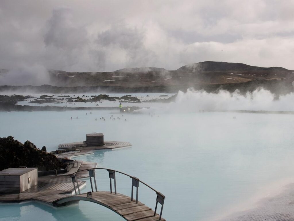 Visitors relaxing in the Blue Lagoon with steam rising from the milky blue water at sunset